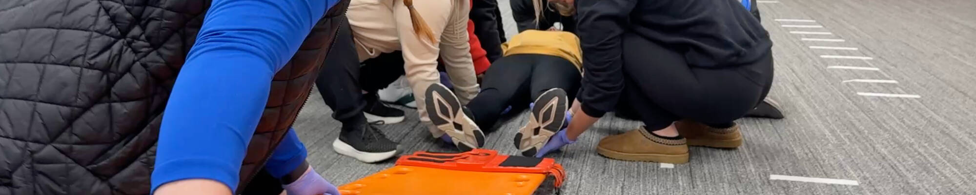 Students practice loading a patient with a spinal injury onto a back board